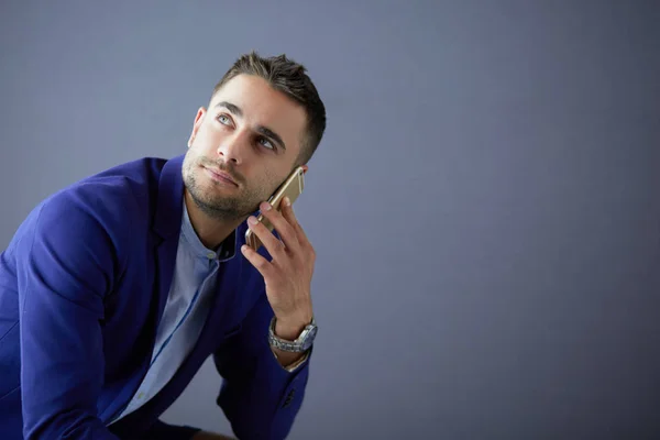 Привлекательный молодой человек со смартфоном на цветном фоне — стоковое фото
