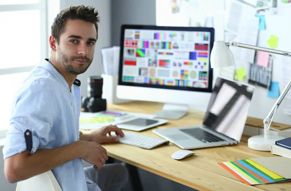 Porträt eines jungen Designers, der im Grafikstudio vor Laptop und Computer sitzt, während er online arbeitet — Stockfoto