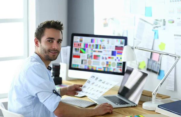 Portrait de jeune designer assis dans un studio graphique devant un ordinateur portable et un ordinateur tout en travaillant en ligne — Photo