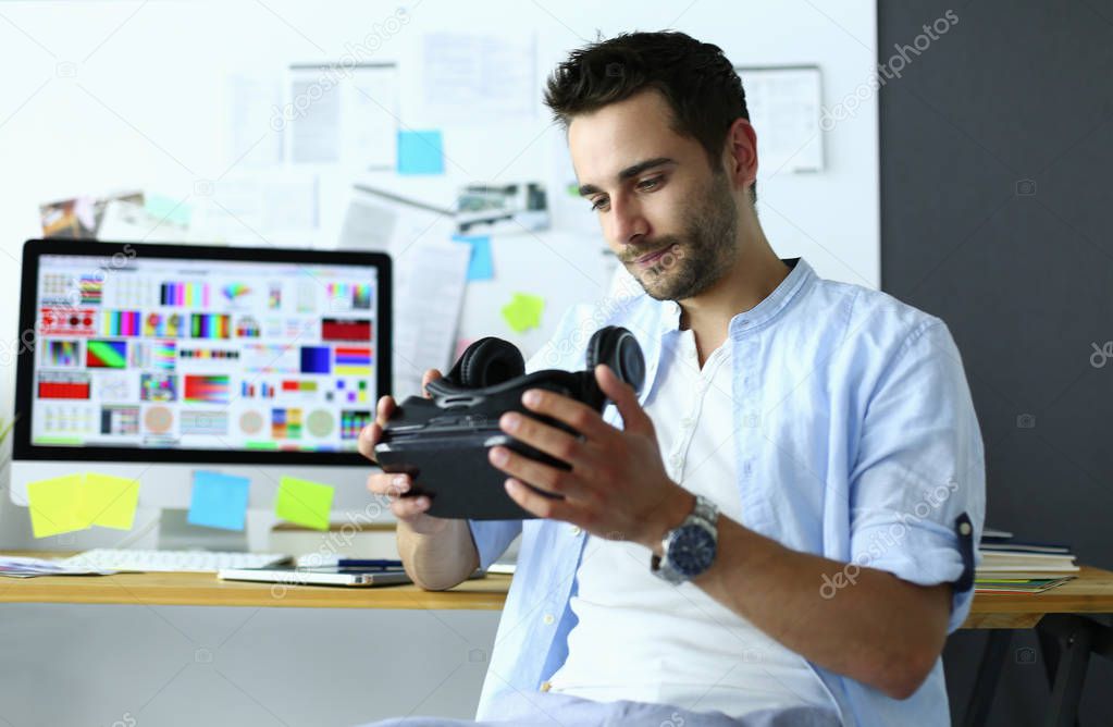 Young male software programmer testing a new app with 3d virtual reality glasses in office