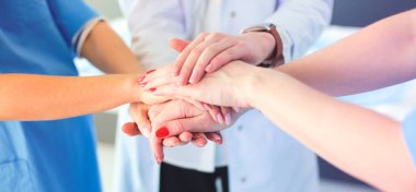 Doktorlar ve hemşireler tıbbi bir ekipte el ele tutuşuyorlar.