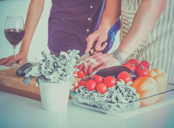 Giovane uomo che taglia verdure e donna in piedi in cucina — Foto Stock