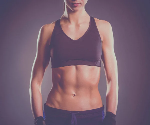 Muscular young woman posing in sportswear against black background — Stock Photo, Image