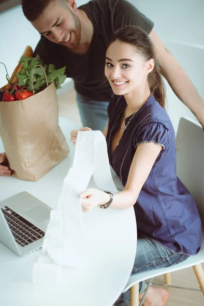 Paret betalar sina räkningar med laptop i köket hemma — Stockfoto