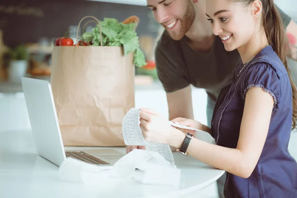 Paret betalar sina räkningar med laptop i köket hemma — Stockfoto
