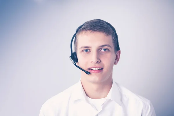 Retrato de un joven sonriendo sentado sobre un fondo gris. Retrato del joven — Foto de Stock