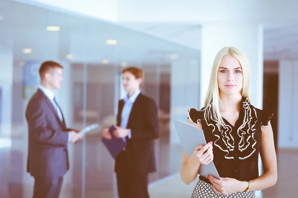 Portret van jonge zakenvrouw in functie met collega 's op de achtergrond . — Stockfoto