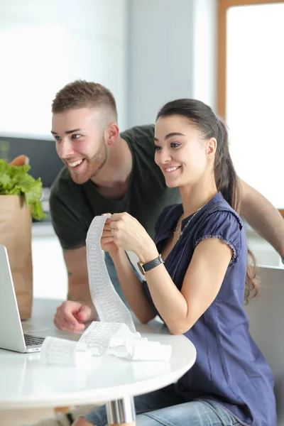 Casal pagando suas contas com laptop na cozinha em casa — Fotografia de Stock