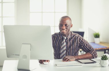 Yakışıklı Afro Amerikalı işadamı Klasik takım elbiseli bir dizüstü bilgisayar kullanarak ve ofiste çalışırken gülümseyen