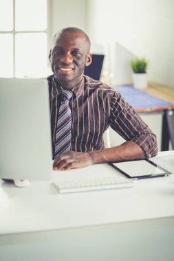 Yakışıklı Afro Amerikalı işadamı Klasik takım elbiseli bir dizüstü bilgisayar kullanarak ve ofiste çalışırken gülümseyen