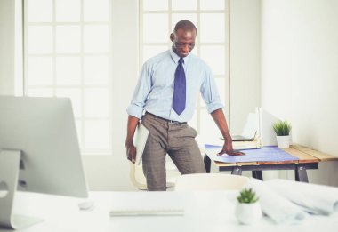 Ofiste bilgisayar ve planlarla çalışan Afrikalı Amerikalı bir mimar.