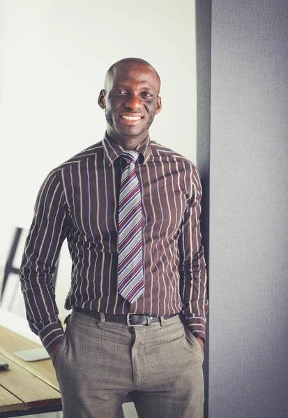 Portret przystojnego, czarnego biznesmena stojącego w biurze — Zdjęcie stockowe