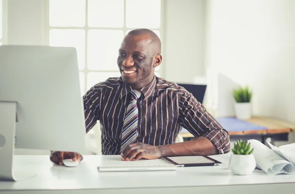 Stilig Afro amerikansk affärsman i klassisk kostym är att använda en laptop och leende medan arbetande i kontor — Stockfoto