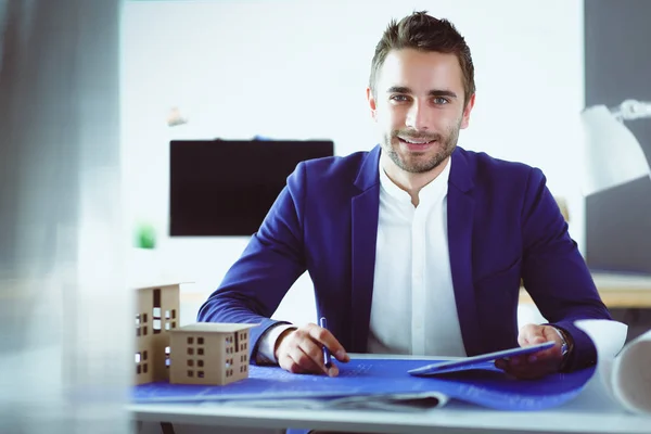 Empresario sosteniendo la casa en miniatura en la mano de pie en la oficina . —  Fotos de Stock