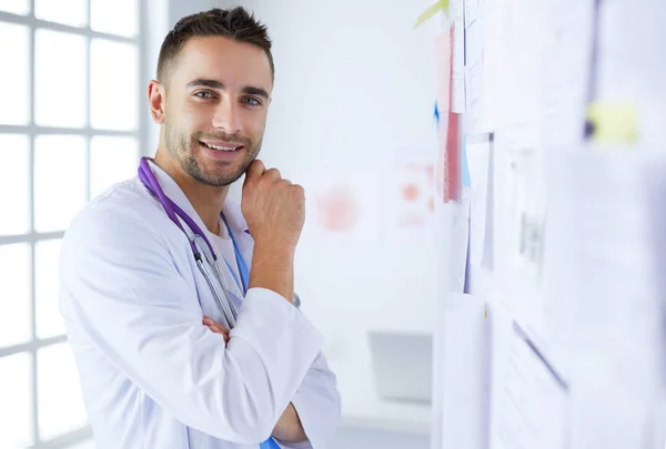 Портрет молодого и уверенного мужчины-врача, стоящего в медицинском кабинете — стоковое фото