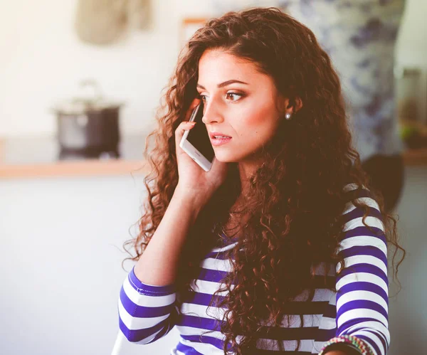 Lachende vrouw met haar mobiel in de keuken. Lachende vrouw — Stockfoto