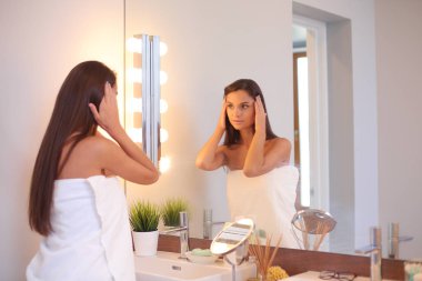 Çekici genç bir kadın yüzüne krem sürüyor..