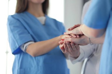 Doktorlar ve hemşireler tıbbi bir ekipte el ele tutuşuyorlar.