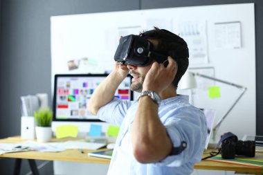 Genç erkek yazılım programcısı ofiste üç boyutlu sanal gerçeklik gözlükleriyle yeni bir uygulama test ediyor..