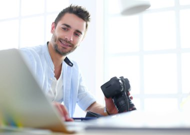 İnternette çalışırken bilgisayarın ve dizüstü bilgisayarın önünde grafik stüdyosunda oturan genç tasarımcının portresi.