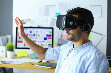 Genç erkek yazılım programcısı ofiste üç boyutlu sanal gerçeklik gözlükleriyle yeni bir uygulama test ediyor..