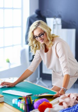 Moda tasarımcısı kadın stüdyoda tasarımları üzerinde çalışıyor.