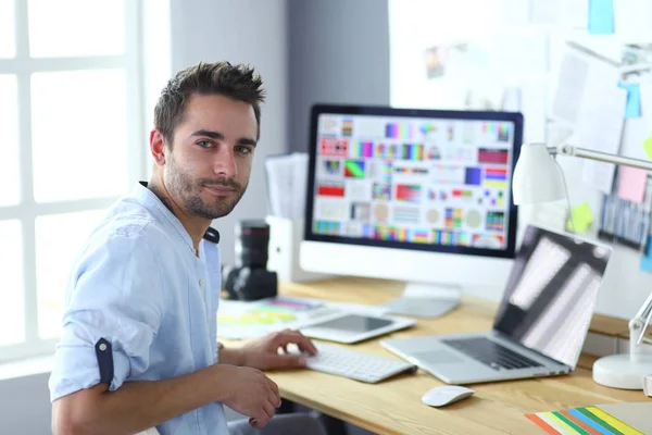 Porträt eines jungen Designers, der im Grafikstudio vor Laptop und Computer sitzt, während er online arbeitet. — Stockfoto