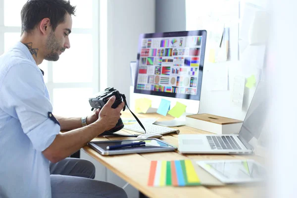 Retrato de jovem designer sentado no estúdio gráfico na frente de laptop e computador enquanto trabalhava online. — Fotografia de Stock