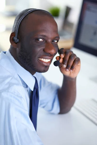 Afrikansk amerikansk affärsman på headset arbetar på sin bärbara dator — Stockfoto