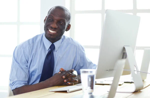 Empresário afro-americano no fone de ouvido trabalhando em seu laptop — Fotografia de Stock
