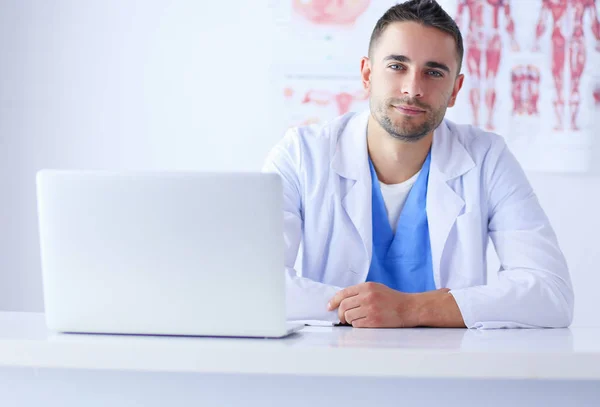 Portrait d'un médecin avec un ordinateur portable assis au bureau médical — Photo