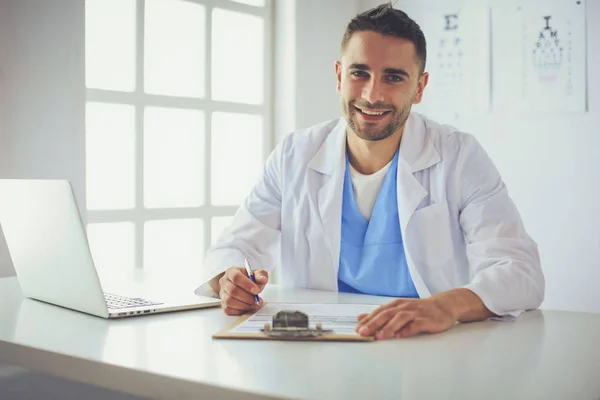 Erkek doktor dizüstü bilgisayar kullanıyor, masasında oturuyor. — Stok fotoğraf