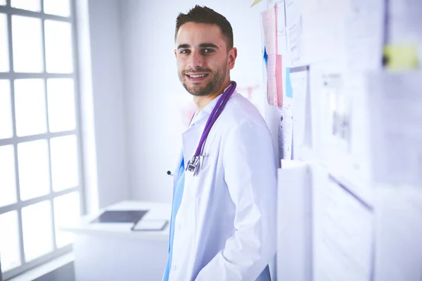 Młody i pewny siebie mężczyzna lekarz portret stojący w gabinecie medycznym — Zdjęcie stockowe