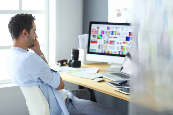 Porträt eines jungen Designers, der im Grafikstudio vor Laptop und Computer sitzt, während er online arbeitet. — Stockfoto