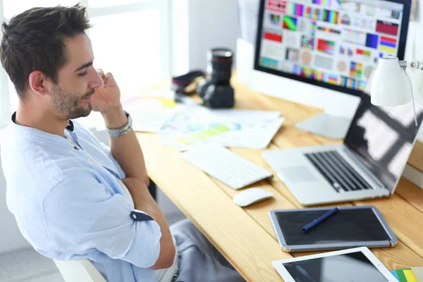 Porträt eines jungen Designers, der im Grafikstudio vor Laptop und Computer sitzt, während er online arbeitet. — Stockfoto