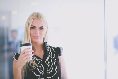 Ofiste bir fincan kahve ayakta tutan işkadını .