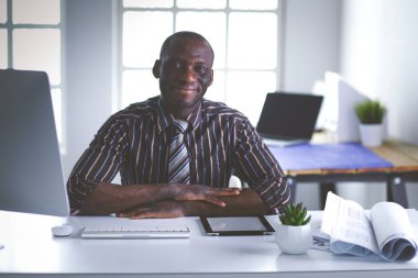 Yakışıklı Afro Amerikalı işadamı Klasik takım elbiseli bir dizüstü bilgisayar kullanarak ve ofiste çalışırken gülümseyen