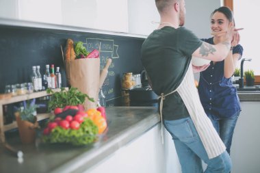 Bir çift evdeki mutfaklarında birlikte yemek pişiriyor.