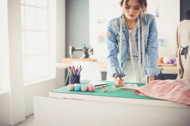 Moda tasarımcısı kadın stüdyoda tasarımları üzerinde çalışıyor.
