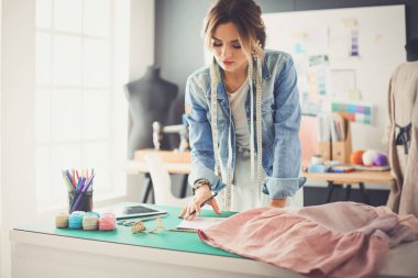 Moda tasarımcısı kadın stüdyoda tasarımları üzerinde çalışıyor.
