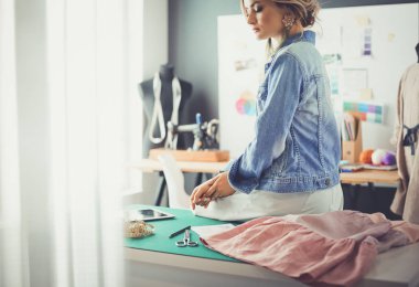 Moda tasarımcısı kadın stüdyoda tasarımları üzerinde çalışıyor.