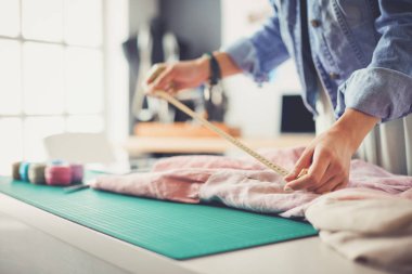 Moda tasarımcısı kadın stüdyoda tasarımları üzerinde çalışıyor.