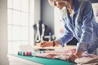Moda tasarımcısı kadın stüdyoda tasarımları üzerinde çalışıyor.