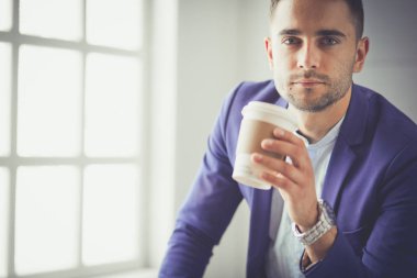 Gri arka planda yalnız oturan genç iş adamı.