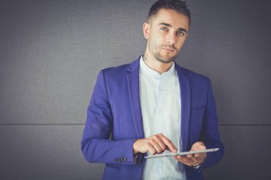 Gri arka planda yalnız oturan genç iş adamı.