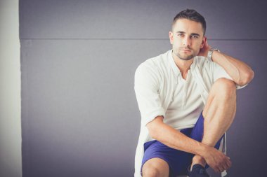 Gri arka planda yalnız oturan genç iş adamı.