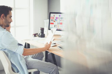 İnternette çalışırken bilgisayarın ve dizüstü bilgisayarın önünde grafik stüdyosunda oturan genç tasarımcının portresi.