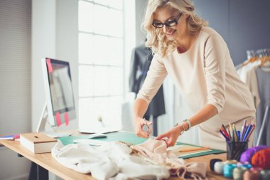 Moda tasarımcısı kadın stüdyoda tasarımları üzerinde çalışıyor..