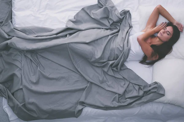 Beautiful brunette lying on bed at home — Stock Photo, Image