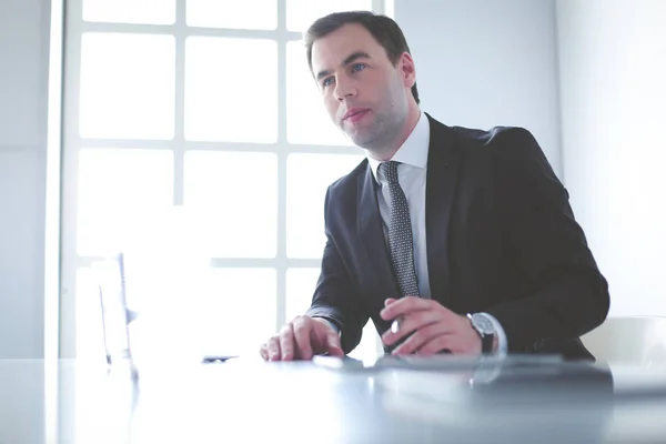 Portrait de jeune homme assis à son bureau dans le bureau. — Photo